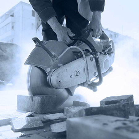 Worker using handheld saw cutting brick